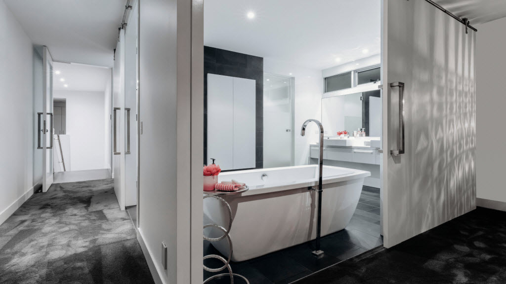 Finished ensuite with a freestanding bathtub, black feature wall and sliding barn door
