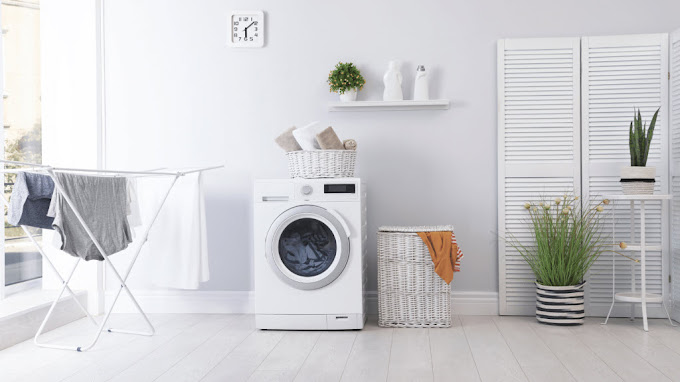 White laundry room with a front-loading washing machine, wicker baskets and a clothes airer